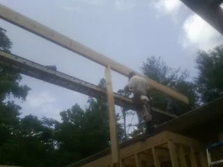Carpenter setting a ridge beam over a new addition frame — Ice Dam Removal by Roofing Brothers in Evansdale