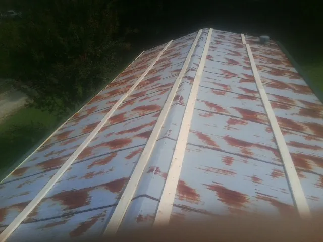 Rusted metal roof panels with new wood purlins before replacement — Storm Damage Roof Repair in Evansdale by Roofing Brothers