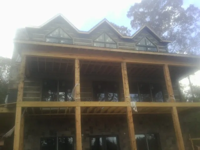 Dormers and porch framing on a large log home under construction — Roof Coating work by our crew in Evansdale