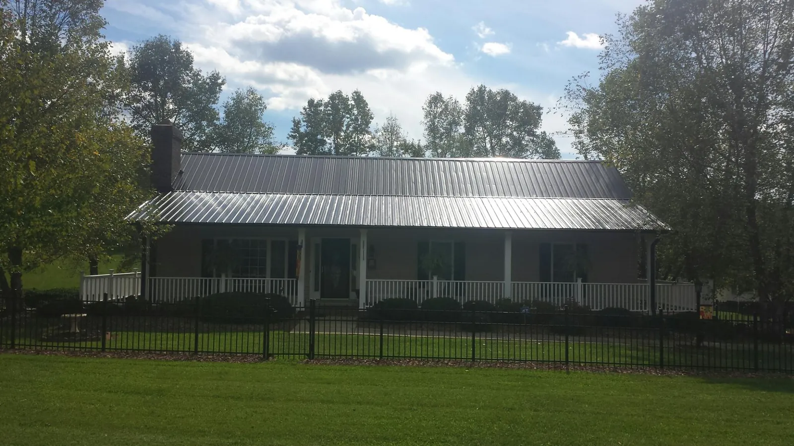Gray metal roof on a brick ranch with a full width front porch — Gutter Guard Installation work by our crew in Evansdale