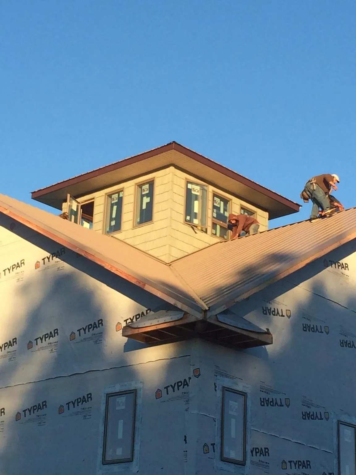 Roofers working around a rooftop cupola on a new metal roof at sunset — Roof Waterproofing in Evansdale by Roofing Brothers